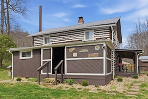A cabin with a wooden exterior, a chimney, a porch, and a sign indicating it is a bed and breakfast.