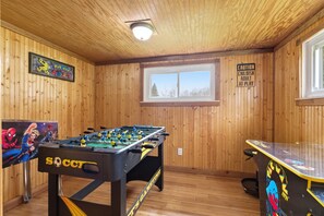 A room with wooden walls, a foosball table, a TV screen, and a caution sign.