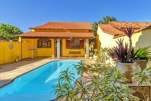 Ein Haus mit Swimmingpool, Ziegeldach und Blumentöpfen.