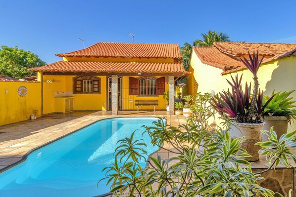 Ein Haus mit Swimmingpool, Ziegeldach und Blumentöpfen.