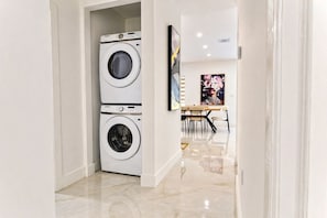 A laundry room with two stacked washing machines and a dining area with a table and chairs. - Spacious 4-bedroom home in peaceful Miami Springs - Sleeps 14 (Miami Springs)