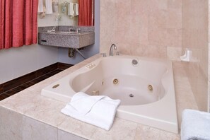 A bathroom with a large bathtub, a granite countertop sink, and a mirror above the sink. - Emerald Inn on Sunset (Los Angeles)