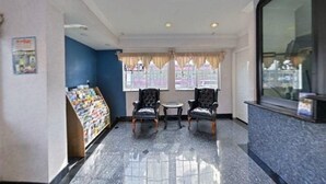 A lobby with a reception desk, two armchairs, a small table, and a magazine rack. - Emerald Inn on Sunset (Los Angeles)