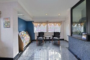 A lobby with a reception desk, two armchairs, a small table, and a magazine rack. - Emerald Inn on Sunset (Los Angeles)