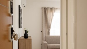 A hallway leading to a living room with a sofa, a wooden side table with a vase, and a door with a lock. - La Dimora Molara by Wonderful Italy (Olbia)