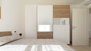 A bedroom with a bed, a wardrobe, a mirror, and a door. - La Dimora Molara by Wonderful Italy (Olbia)