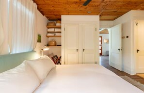 Ein Schlafzimmer mit einem Bett, einem Nachttisch, einer Lampe, einem Kleiderschrank und einer Tür zu einem anderen Raum.
