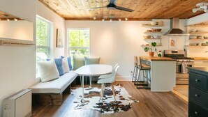 Una cocina moderna con vigas de madera, un comedor con alfombra de cuero de vaca y un banco empotrado con cojines.