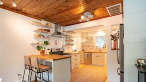 Una cocina moderna con armarios de madera, una isla central y un comedor con sillas.