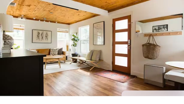 Amplia sala de estar con piso de madera, un sofá, una mesa de centro y una mesa de comedor.