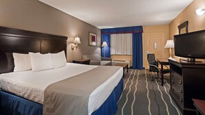 A hotel room with a large bed, a desk with a chair, a television, and a window with curtains. - Red Roof Inn & Suites Irving - DFW Airport South (Irving)