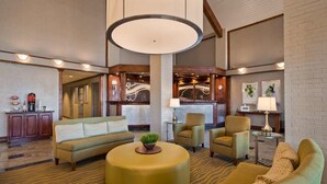 A spacious lobby with a sofa, armchairs, a round ottoman, and a coffee station. - Red Roof Inn & Suites Irving - DFW Airport South (Irving)