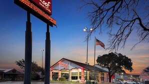 A Red Roof Inn with a large illuminated sign, an American flag, and a clear sky. - Red Roof Inn & Suites Irving - DFW Airport South (Irving)