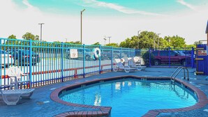 A swimming pool with a blue fence, lounge chairs, and a lifebuoy. - Americas Best Value Inn Irving Dfw Airport South (Irving)