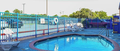 A swimming pool with a blue fence, lounge chairs, and a lifebuoy.