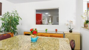 A kitchen with granite countertops, a dining table, chairs, a potted plant, and a mirror above the sink. - Americas Best Value Inn Irving Dfw Airport South (Irving)