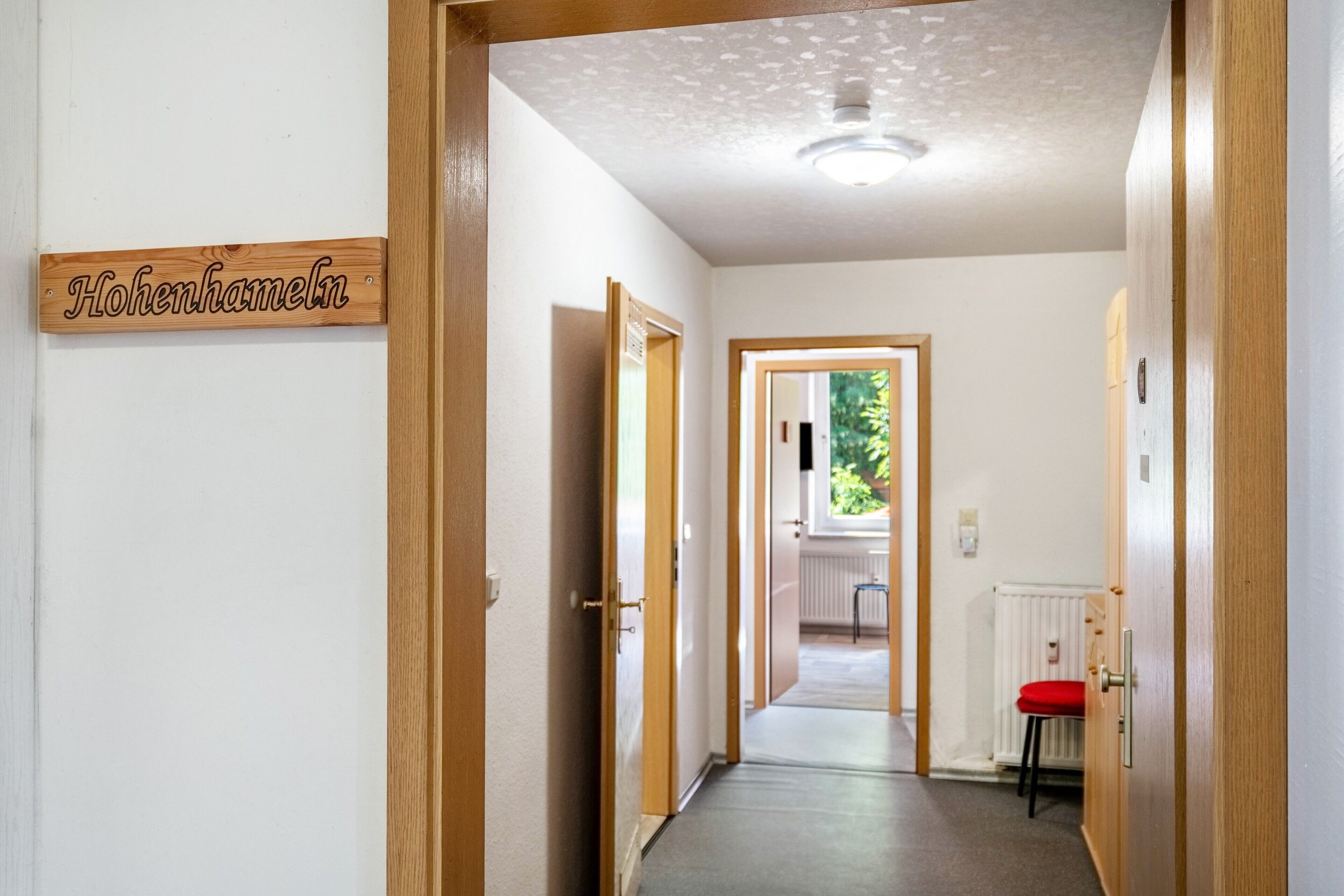 Ein Korridor mit einem Holztürrahmen, einem Schild mit der Aufschrift 'Hohenhameln' und Blick in einen weiteren Raum.