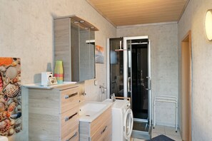 A bathroom with a wooden vanity, a sink, a mirror, a shower, and a toilet.