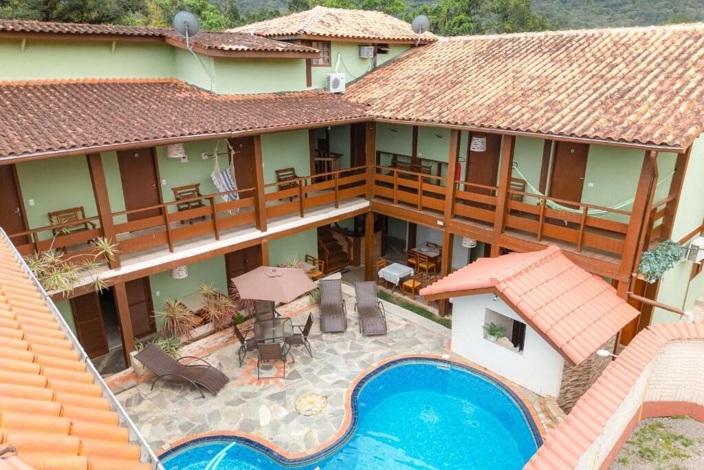 A hotel with a swimming pool, outdoor seating, and a covered patio area.