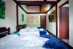 Habitación de hotel con dos camas, techo de madera, decoración verde en la pared y una puerta con espejo.