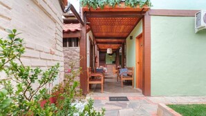 A covered outdoor seating area with chairs and a table, a stone pathway, and a green wall. - VELINN Pousada Kyrios (São Sebastião)
