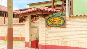A building with a sign reading 'Kyrios Pousada' and a brick wall. - VELINN Pousada Kyrios (São Sebastião)