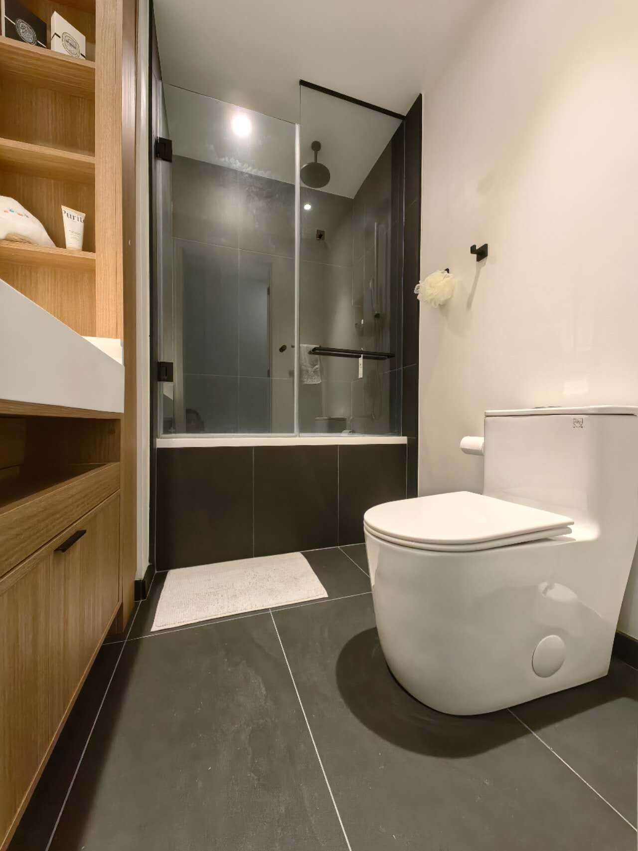A modern bathroom with a toilet, a shower, and a glass-enclosed shower area.