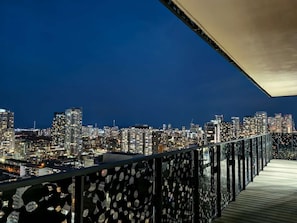 A cityscape at night with a balcony featuring a patterned railing.