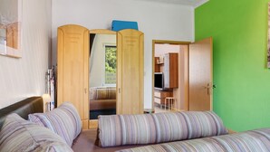 A room with a bed, a wooden wardrobe, a green wall, and a door leading to another room. - Spacious Apartment for up to 5 Guests (72 m²) in Hohenhameln (Hohenhameln)