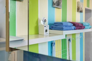 A bathroom with striped walls, a towel rack, and a shelf with folded towels and a camera. - Spacious Apartment for up to 5 Guests (72 m²) in Hohenhameln (Hohenhameln)