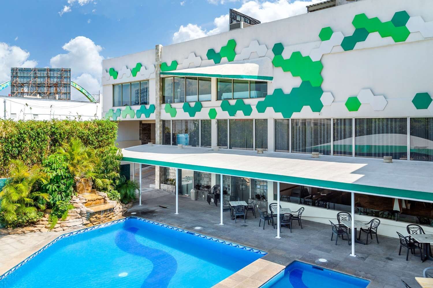 Un edificio moderno con piscina, zona de estar exterior y una decoración en colores verde y blanco.
