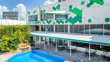 Un edificio moderno con piscina, zona de estar exterior y una decoración en colores verde y blanco.