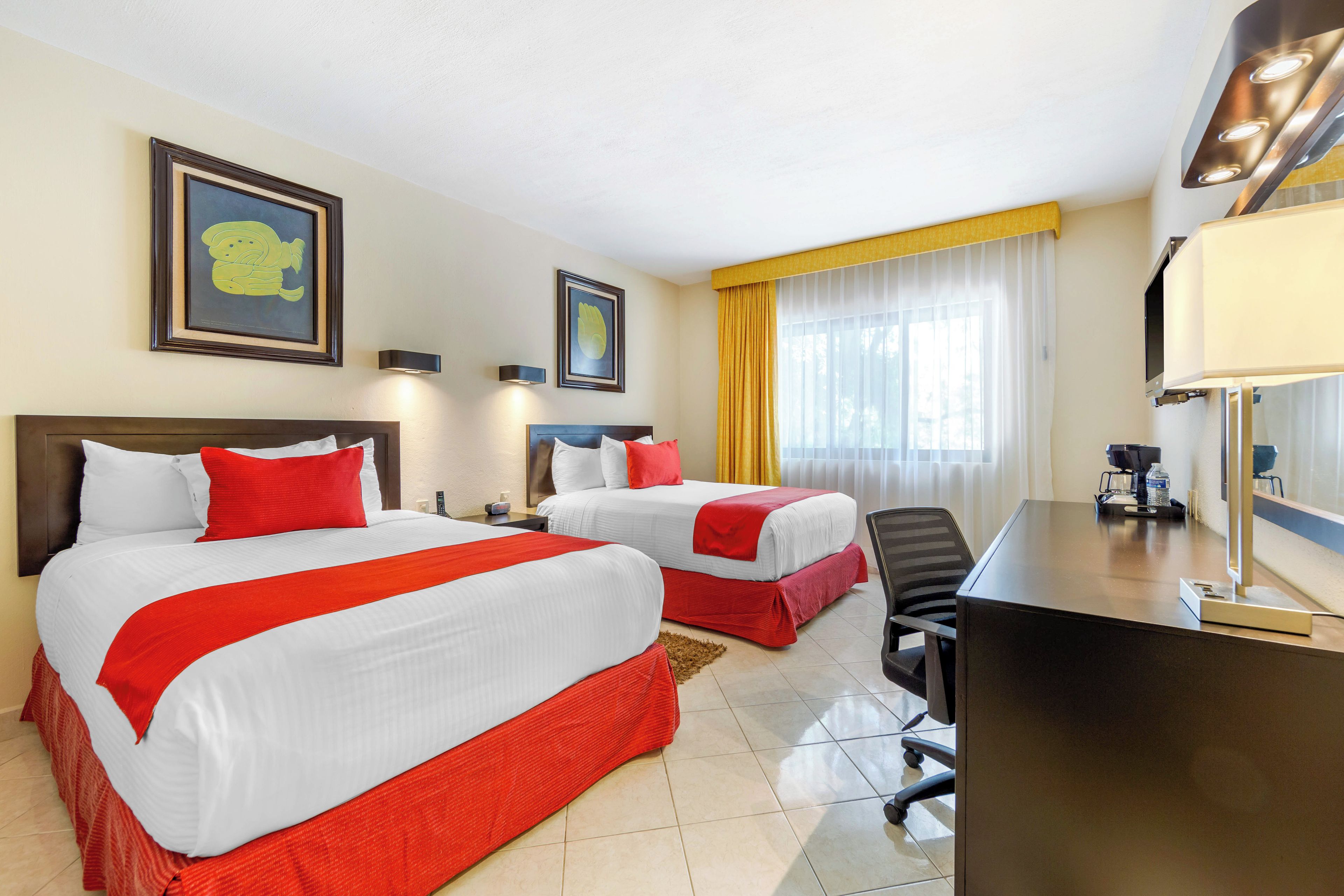Una habitación de hotel con dos camas, un escritorio, una silla y una ventana con cortinas.