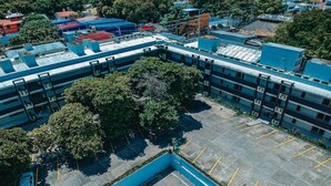 Vista aérea de un estacionamiento con múltiples espacios y un edificio con techo azul.