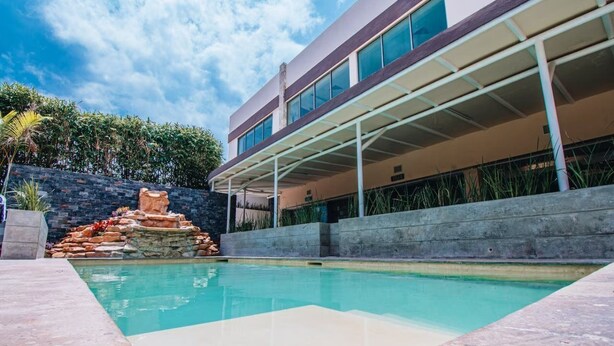 Un edificio moderno con piscina, detalles de piedra y un patio cubierto.
