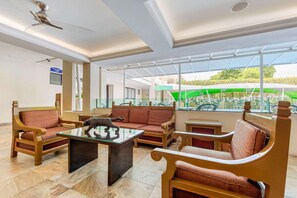A hotel lobby with a seating area, a ceiling fan, and a view of the outdoor area. - Eco City Hotel (Tuxtla Gutierrez)