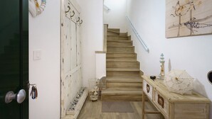 Una scala con gradini in legno, una parete bianca con un quadro e un tavolino con oggetti decorativi.