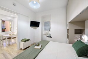Ett modernt hotellrum med en säng, ett skrivbord, en stol, en tv och ett badrum.