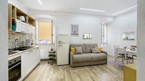 Una cucina compatta con mobili bianchi, forno a incasso, microonde e frigorifero.