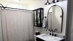 A bathroom with a toilet, sink, mirror, and shower curtain.