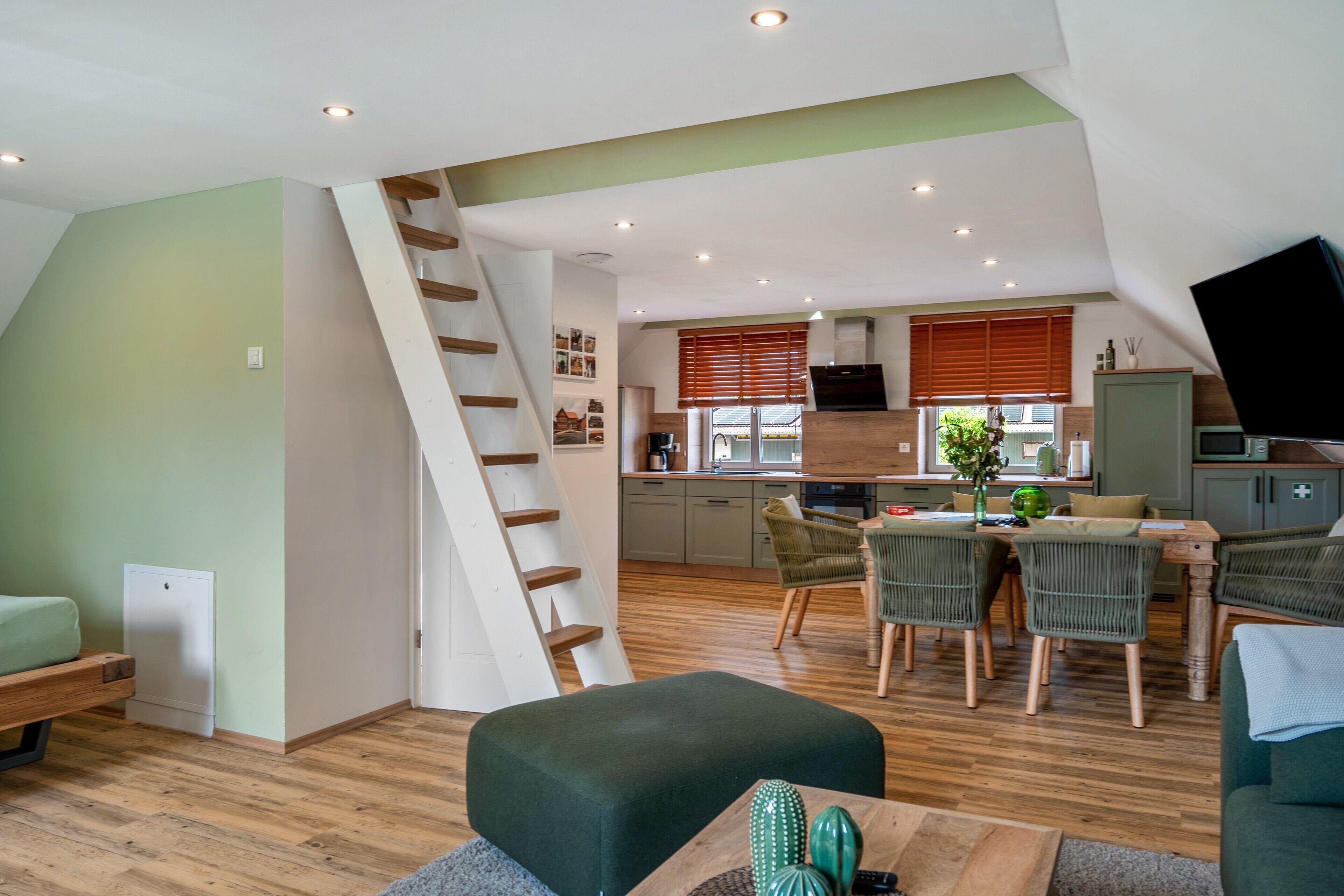 Un apartamento estilo loft con comedor, cocina y una escalera que lleva a un nivel superior.