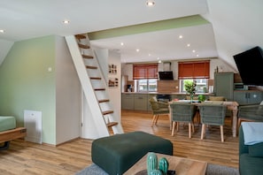 Un appartement de style « loft » comprenant un coin repas, une cuisine et un escalier menant à un niveau supérieur.