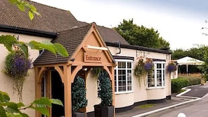 A building with an entrance sign, a pitched roof, and a window with a hanging flower basket. - Premier Inn Solihull South Hotel (Solihull)