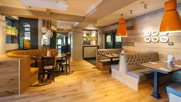 A modern interior with a wooden floor, a round table with chairs, and a sofa. - Premier Inn Solihull South Hotel (Solihull)