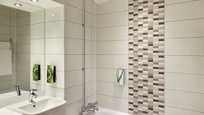 A modern bathroom with two sinks, a shower, and a tiled wall with a mosaic pattern. - Premier Inn Solihull South Hotel (Solihull)