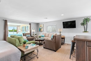 A modern living room with a sofa, armchairs, a coffee table, and a TV. - Tropical Waterfront Grande Suite with Private Balcony in Bonita Springs (Bonita Springs)