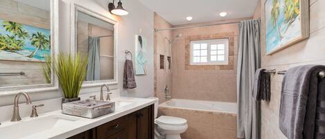 A bathroom with a bathtub, toilet, sink, and mirrors.