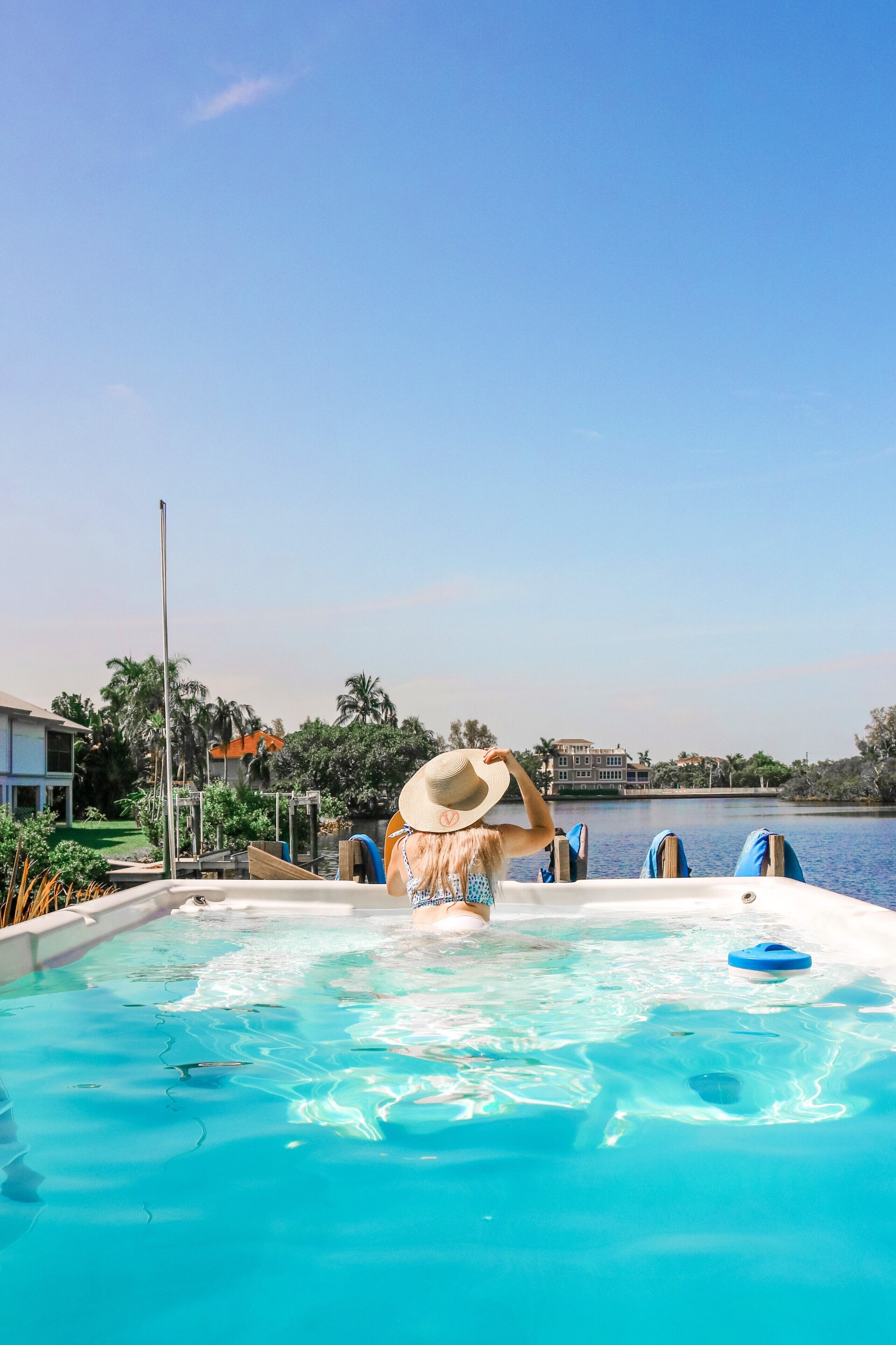 Une piscine avec une eau d’un bleu limpide, une personne dans l’eau et une vue sur un bâtiment situé de l’autre côté.