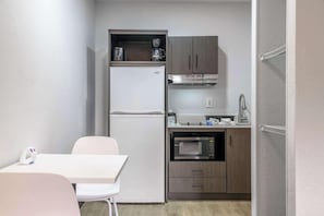 A compact kitchenette with a refrigerator, microwave, and a coffee maker. - Studio6 Columbus, GA Columbus Airport (Columbus)