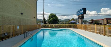 A swimming pool with a no smoking sign, a Travelodge sign, and a fenced area.